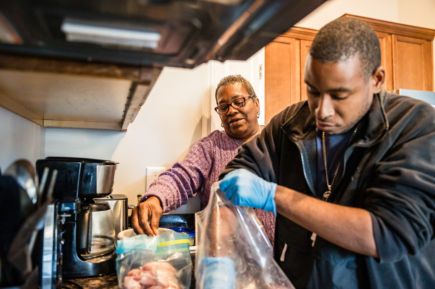 A residential services volunteer assists a Unity Bay member in the kitchen while both are cooking.